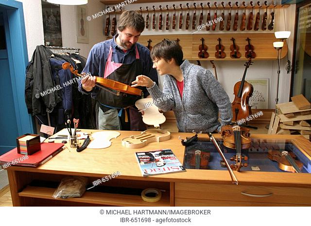 Violin-maker (luthier) with a customer in his shop