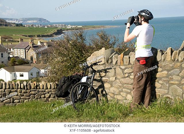 Young male cyclist taking photograph of Aberarth village on the cardigan bay coast near Aberaeron, ceredigion, west Wales UK