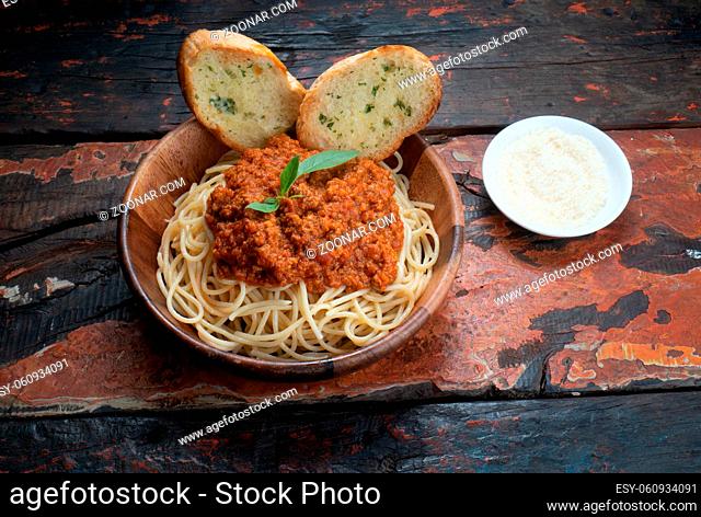 Spaghetti bolognese pasta with tomato sauce and minced meat, grated parmesan cheese and fresh basil. Homemade healthy italian pasta with toasted garlic bread on...