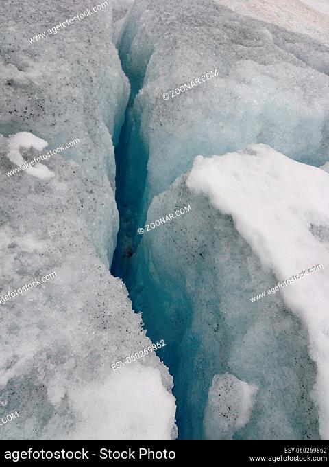 Crack in the ice of a glacier due to global warming and climate change. Melting snow causing sinkhole
