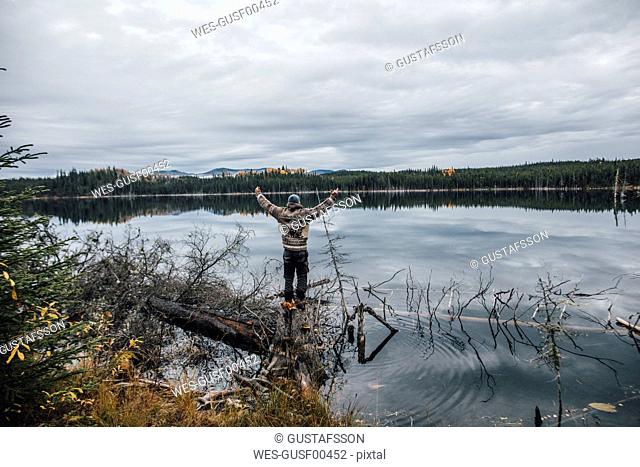 Canada, British Columbia, man standing at Blue Lake raising his arms