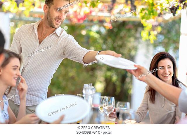 Man passing plate at outdoor family lunch