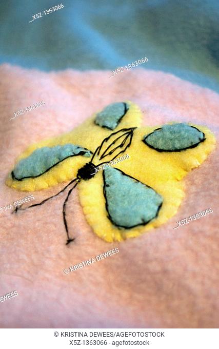 A yellow and blue butterfly appliqued on a baby quilt made of fleece