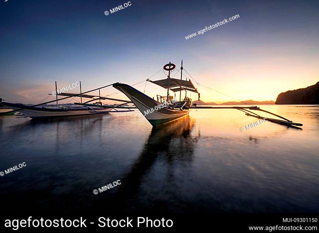 Tropical harbor bay in evening. Golden hour in lagoon in Philippines, Palawan, El Nido. Sunset on beach. Tranquil scenic sundown above mountains islands on...