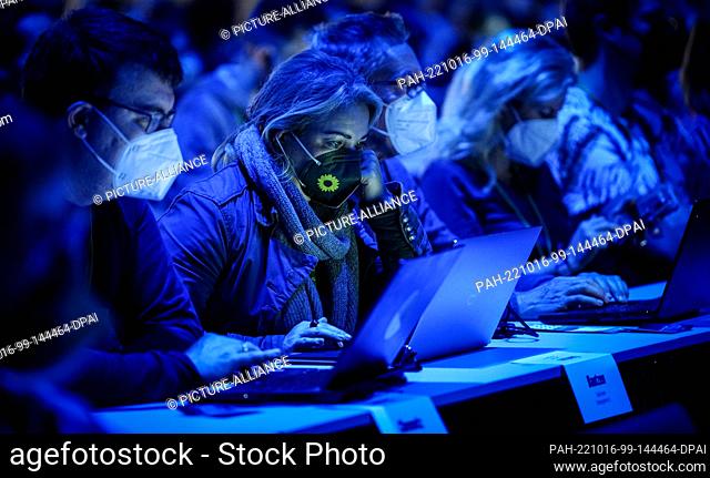 16 October 2022, Bonn: Delegates wearing FFP2 masks sit at their laptops in the darkened event hall at the Green Party's national convention