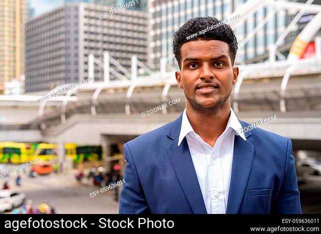 Portrait of African businessman looking at camera while in city horizontal shot