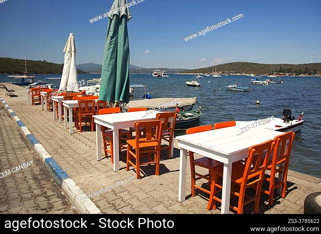 Tables and chairs of a restaurant by the sea in Sigacik town, Seferihisar, Izmir, Aegean Coast, Turkish Riviera, Turkey, Europe