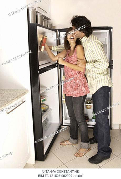 Hispanic couple looking in refrigerator