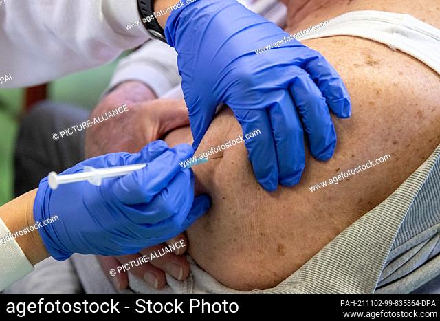 02 November 2021, Bavaria, Erlangen: An elderly man receives a booster vaccination against Covid-19 in a temporary mobile vaccination centre