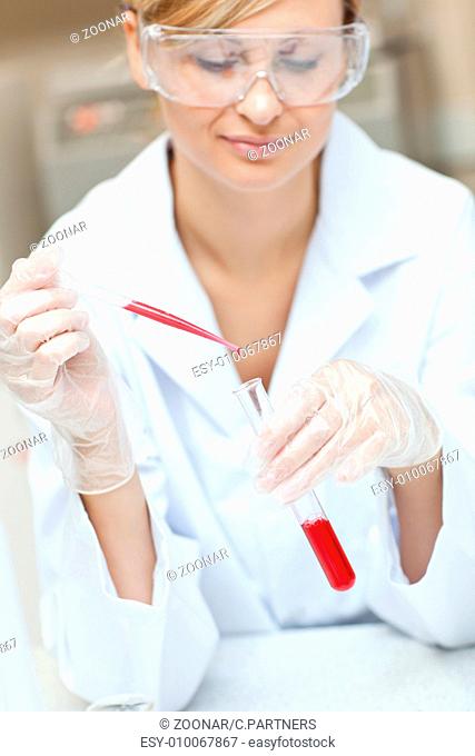 Close-up of a concentrated female scientist putting liquid in a test tube with a pipette