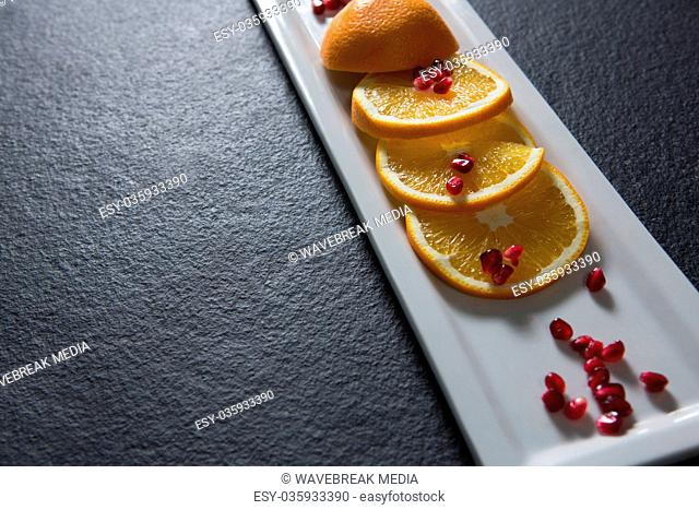 Slice of orange with pomegranate seeds in tray