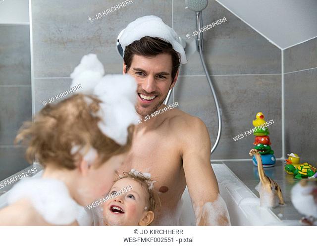 Father having fun with sons in bathtub