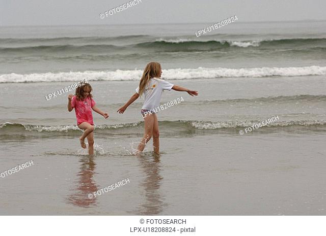 Two girls playing on ocean beach