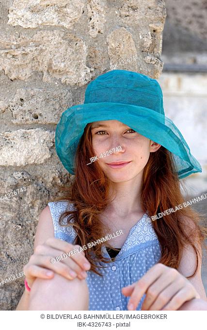 Red-haired girl with a turquoise sun hat smiling, portrait, Italy