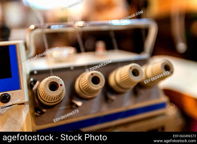 A closeup view of the spool control dials on a vintage overlock machine. Old-fashioned retro machinery of a seamstress inside atelier
