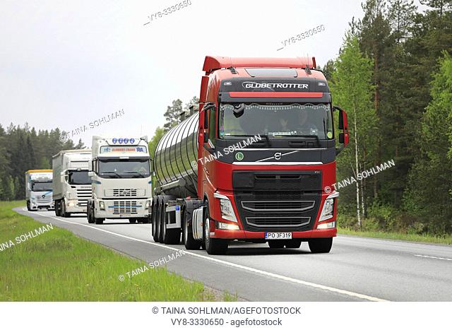 Raasepori, Finland. May 24, 2019. Fleet of four heavy trucks led by a red Volvo FH 500 semi tanker on highway on a cloudy day of summer in Finland