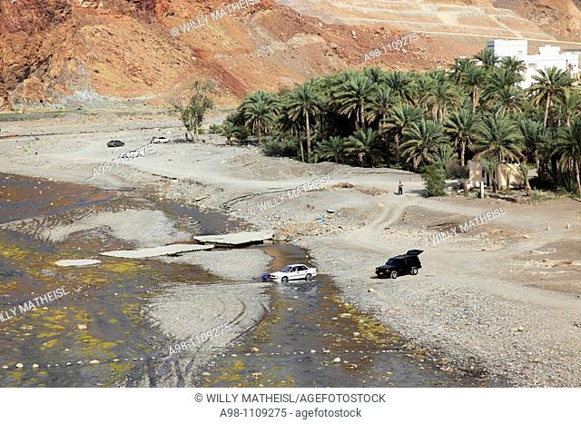 car stuck in river runlet in wadi with date palms at the village of Fanja, Hajar al Gharbi, Sultanate of Oman, Asia
