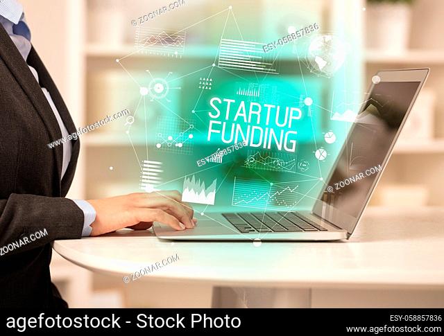 Side view of a business person working on laptop with STARTUP FUNDING inscription, modern business concept