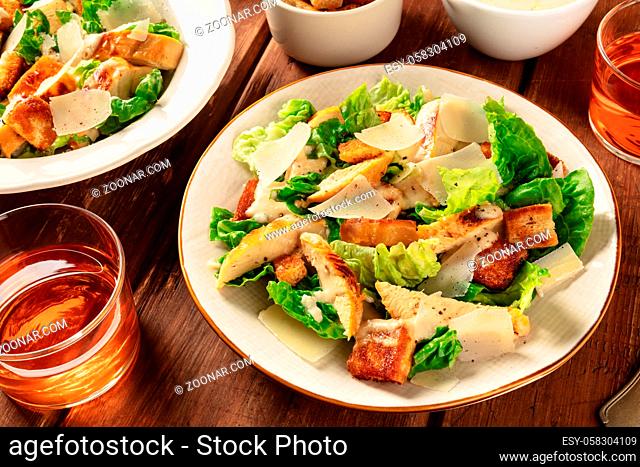 Caesar salad with a wine glass on a dark rustic wooden background