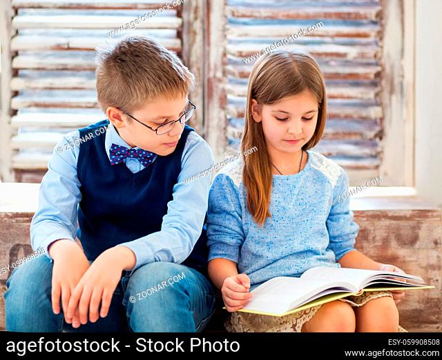 Brother and sister reading book in living room