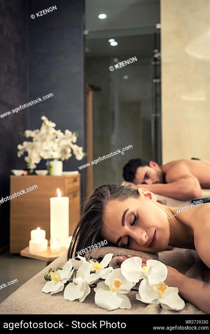 Young couple relaxing under the stimulating effects of a traditional hot stone massage at luxury spa and wellness center