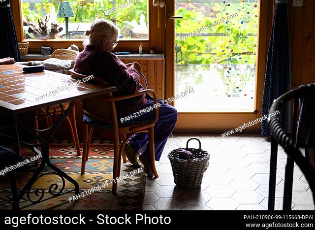 27 August 2021, Thuringia, Zella-Mehlis: An old lady sits in a chair by the window or door to the terrace and knits. Photo: Soeren Stache/dpa-Zentralbild/dpa