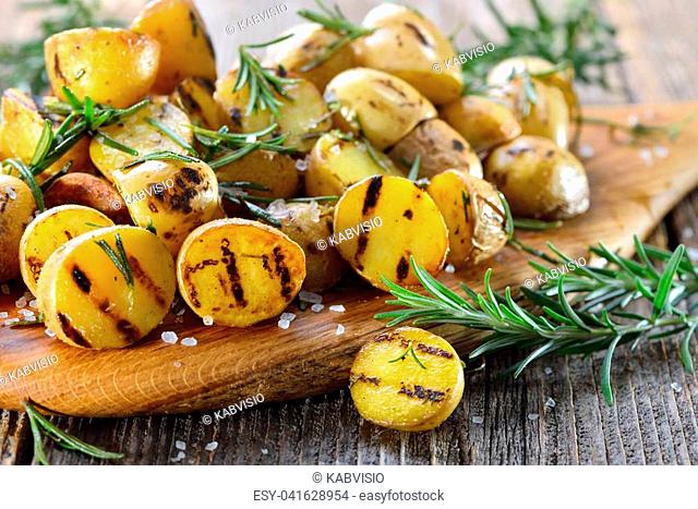 Vegan cuisine: Grilled baby potatoes with rosemary served on a wooden board