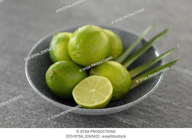 close up of limes in bowl on slate table top