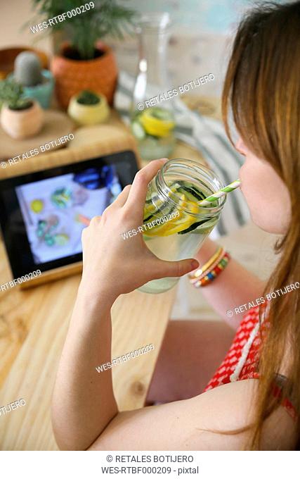 Woman drinking detox water infused with lemon and cucumber