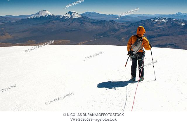 Climber on the summit of Sajama Volcano. The highest mountain in Bolivia (on the horizon Pomerape and Parinacota volcanoes) Sajama National Park