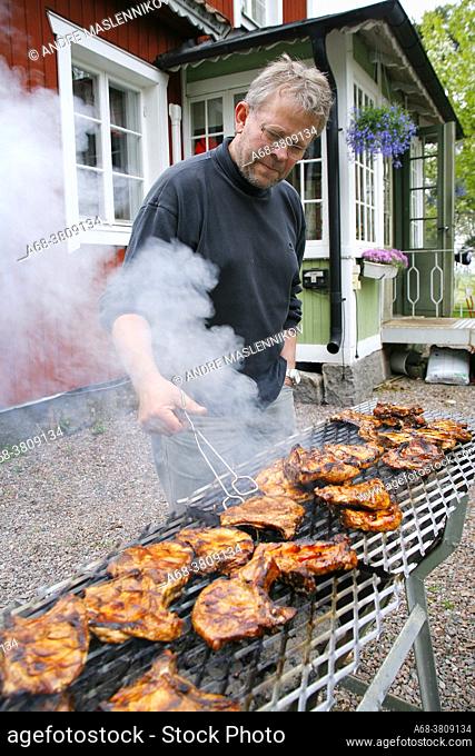 A man grills pork chops on a large grill in the spring