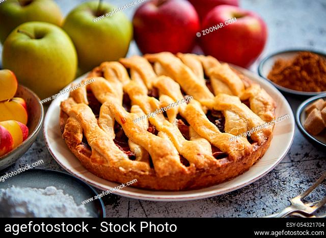 Fresh baked tasty homemade apple pie cake with ingredients on side. Cinnamon sticks, red and green apples, walnuts and anise