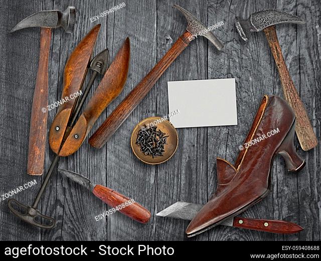 vintage ladies shoe and shoemakers tools over wooden table, space for your text on a blank business card