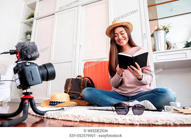 Asian young female blogger recording vlog video with vacation preparing to travel trip at home. online influcencer on social media concept