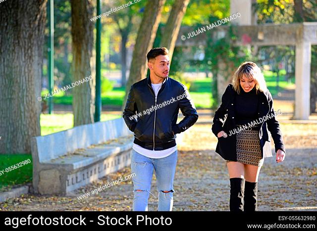 Two young friends walking and talking in a park