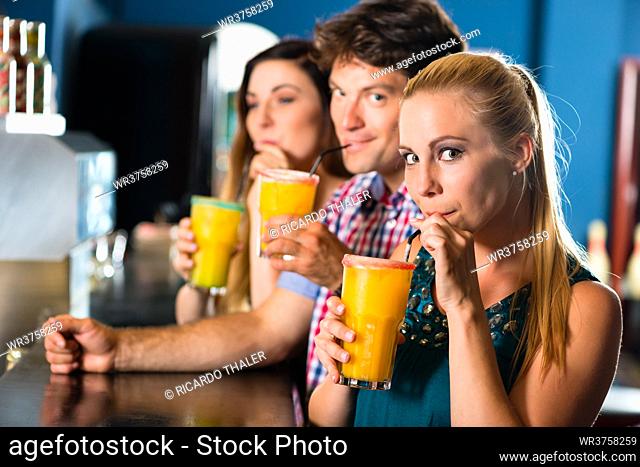 Young people in club or bar drinking cocktails and having fun