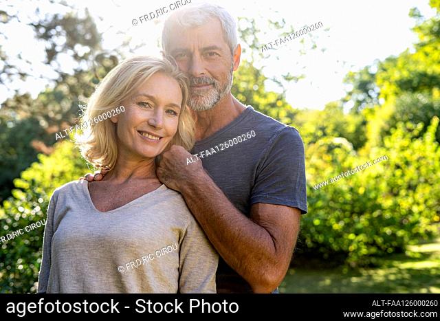Portrait of smiling mature couple standing in backyard