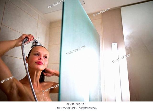 Young woman washing her hair with shampoo, taking a hot long shower