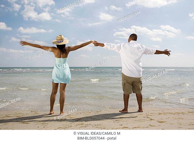 African couple with arms outstretched at beach