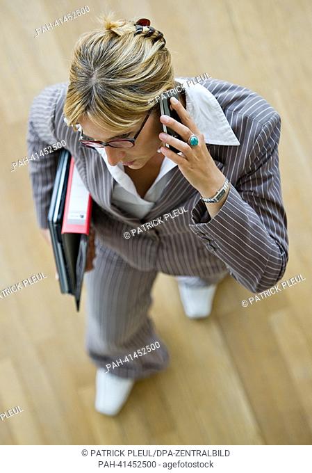 (ILLUSTRATION) An illustration shows a business woman with a folder and laptop under her arm while talking on a smartphone in Frankfurt Oder, Germany