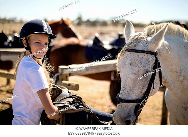 Girl standing next to the white horse in the ranch