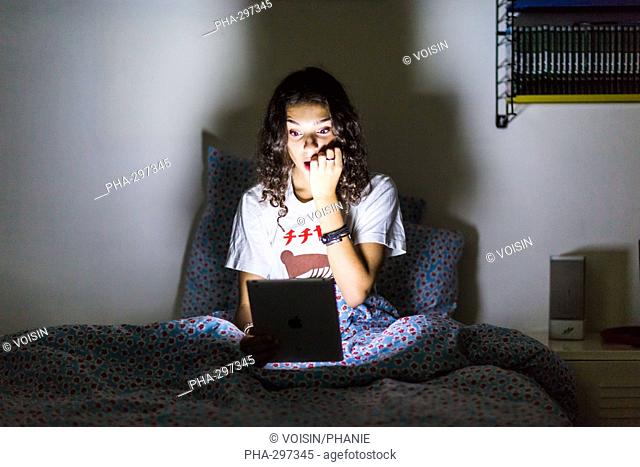 Teenage girl using a digital tablet at night