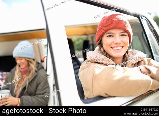 Portrait happy young woman on road trip at van window