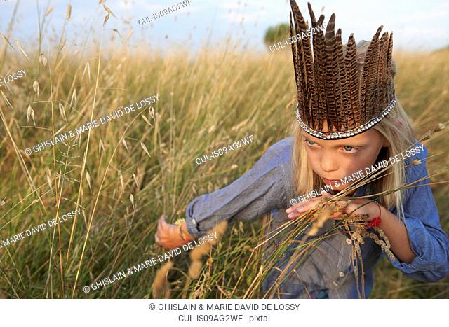 Girl hiding in long grass dressed up as a native american