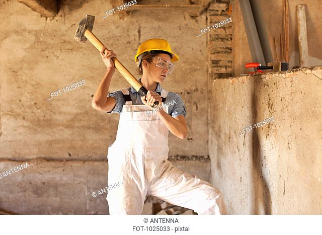 A female construction worker swinging a sledgehammer
