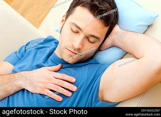 Young handsome man sleeping on couch at home, high-angle view