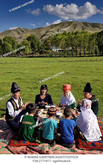 Kazakh family in traditional clothes praying before eating at a picnic in Saty Kazakhstan