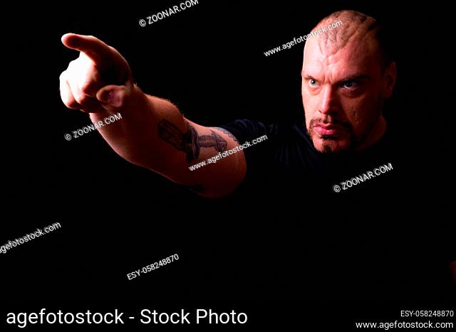 Studio shot of muscular bald bearded man looking macho against black background