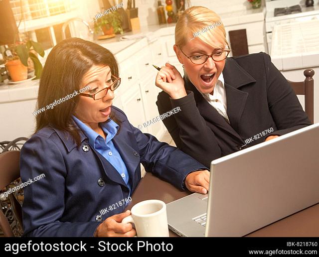 Businesswomen celebrate success on the laptop in the kitchen