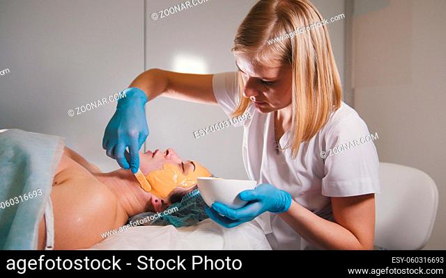 Young woman passes treatment fruit mask facial at the beauty salon, close up